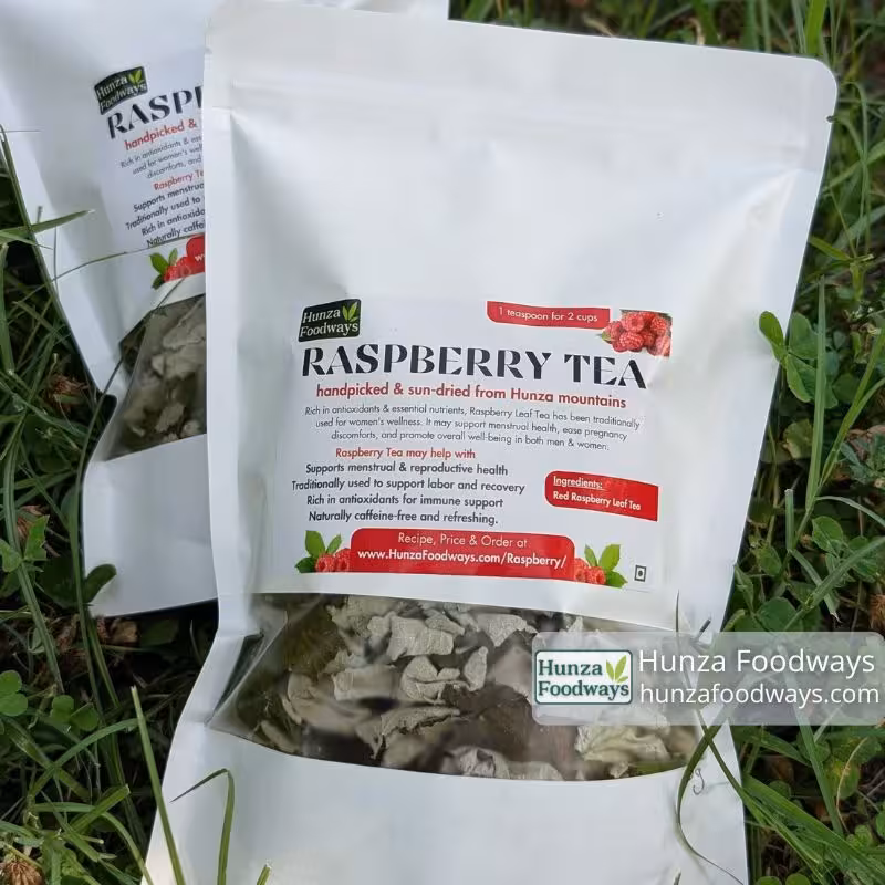 Two pouches of caffeine-free raspberry leaf herbal tea from Hunza Foodways lying in clover and grass