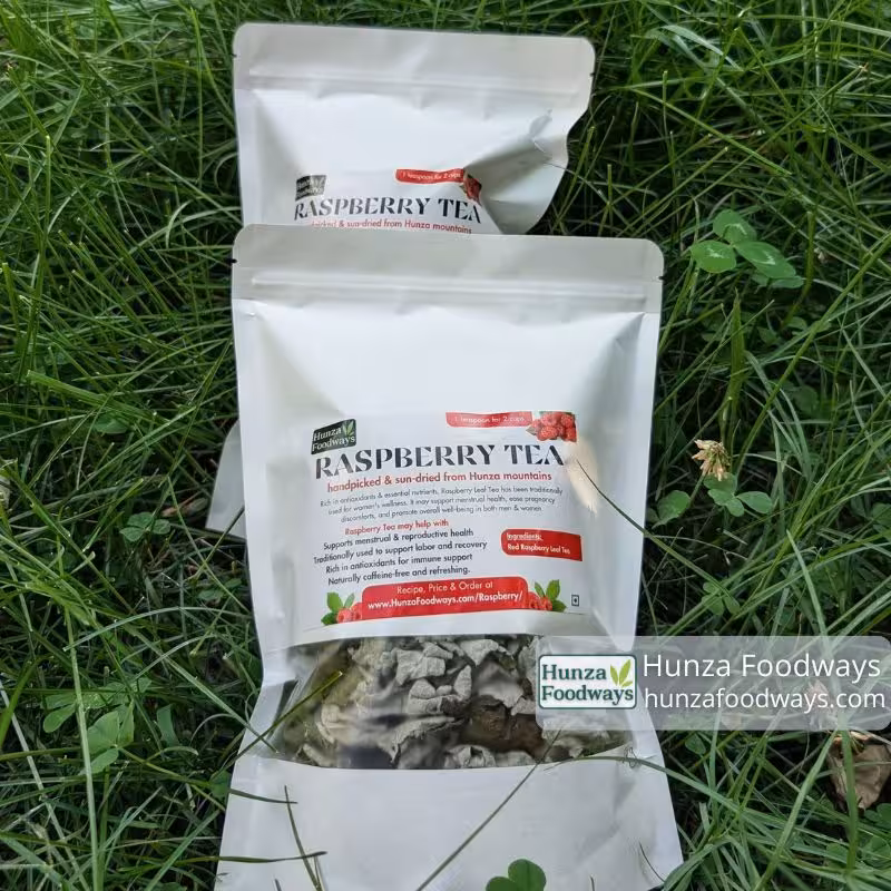 Two Hunza Foodways raspberry leaf tea pouches resting on mountain grass